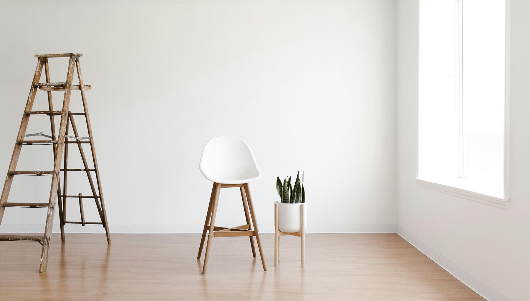 nyrenoverat rum med en stege, stol och en grön planta